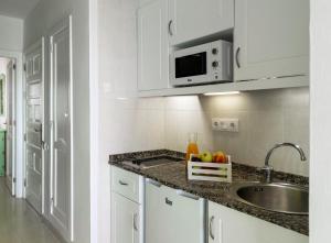 cocina blanca con fregadero y microondas en Apartamentos Hesperia Bristol Playa en Corralejo