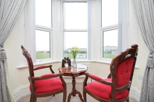 two chairs and a table in a room with windows at The Beach House Luxury Rooms Weston Super Mare in Weston-super-Mare