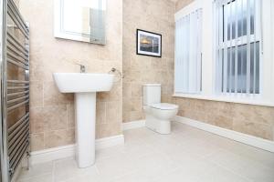 a bathroom with a toilet and a sink and a window at The Beach House Luxury Rooms Weston Super Mare in Weston-super-Mare
