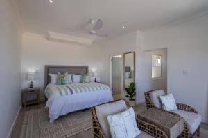 a bedroom with a bed and a couch and a chair at Endless Summer Villa in Plettenberg Bay +30 photos