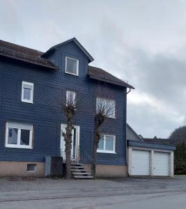 een blauw huis met twee bomen ervoor bij Ferienappartment & Ferienwohnung Banfetal in Bad Laasphe