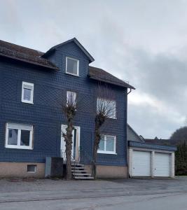 niebieski dom z dwoma drzewami przed nim w obiekcie Ferienappartment & Ferienwohnung Banfetal w mieście Bad Laasphe