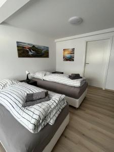 2 letti in una camera con pareti bianche e pavimenti in legno di Ferienappartment & Ferienwohnung Banfetal a Bad Laasphe