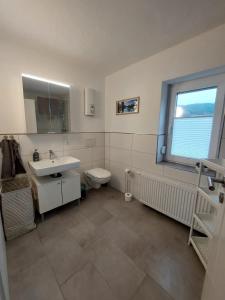 a bathroom with a sink and a toilet and a window at Ferienappartment & Ferienwohnung Banfetal in Bad Laasphe