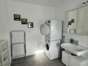 a white bathroom with a washing machine and a sink at Ferienappartment & Ferienwohnung Banfetal in Bad Laasphe