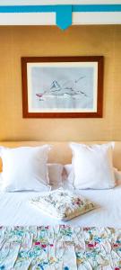uma cama com almofadas brancas e um quadro na parede em Domaine du Châtelard em Dirac