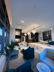 una sala de estar con sofás azules, mesas y ventanas en Hotel ALdoliaa en Unayzah