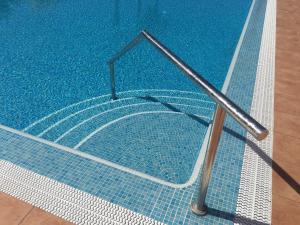 a swimming pool with a metal hand rail in it at Sunset over the sea in Playa de las Americas