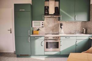a kitchen with green cabinets and a stove at Fritz' FeWo in Veldenz