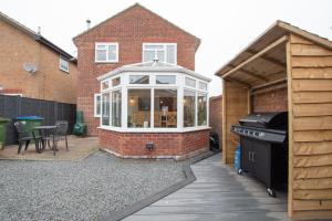 a house with a conservatory and a grill in a yard at Titchfield House in Titchfield