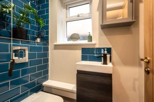 a bathroom with blue tiles and a toilet and a window at Titchfield House in Titchfield