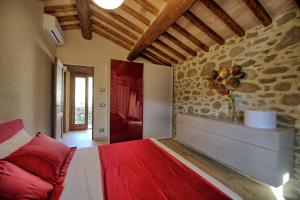 a bedroom with a red bed and a stone wall at Villa Mulino by PosarelliVillas in Poggioni +23 photos