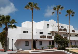 a building with palm trees in front of it at Apartamentos Hesperia Bristol Playa in Corralejo