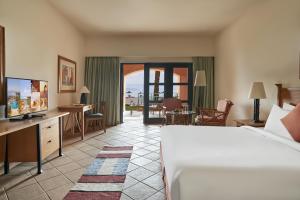 una camera d'albergo con letto e scrivania con TV di Strand Beach Resort a Taba