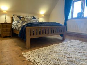 a bedroom with a bed with a blue blanket and a rug at Upper Home Farm in Plaish