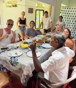 un grupo de personas sentadas alrededor de una mesa comiendo en Colonial Surfing Villa Hostel & Home Stay, en Midigama East