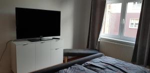 ein Schlafzimmer mit einem TV auf einem weißen Schrank mit einem Stuhl in der Unterkunft Ilmenauer Ferienwohnung in Ilmenau