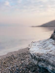 a rock sitting on a beach next to the water at שלווה בים - צימר ים המלח, deadsea in Ovnat