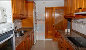 a kitchen with wooden cabinets and a sink at APARTAMENTO ZEN. TEULADA. LIVE IT COSTABLANCA in Teulada