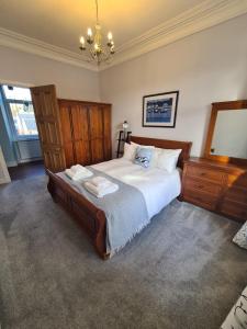 a bedroom with a large bed and a chandelier at The Editor's Choice, Oban seafront apartment in Oban