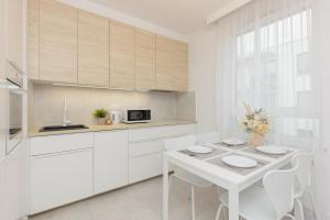 a kitchen with white cabinets and a white table and chairs at Warsaw Piaseczno Peaceful Apartment Cichej Łąki by Renters in Piaseczno