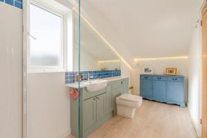 a bathroom with a sink and a toilet and a window at The Old Barn in Witney