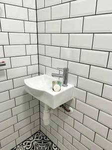 a white sink in a white tiled bathroom at Flat 4, 10 St John's in Bournemouth
