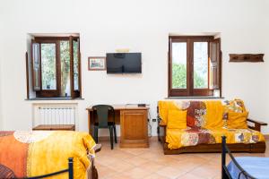 a bedroom with a couch and a desk and a tv at Agriturismo Casa Scola in Gragnano