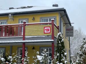 una casa gialla con un cartello con il numero di Guest House Mr Fox a Druskininkai