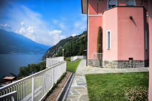 a pink building next to a body of water at Villa Perledina by Wonderful Italy in Perledo