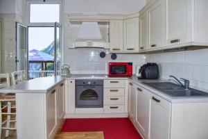 cocina con armarios blancos y microondas rojo en Villa Perledina by Wonderful Italy en Perledo