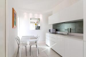 cocina con armarios blancos, mesa y sillas en Residence Saint Nicholas, en Lido di Jesolo