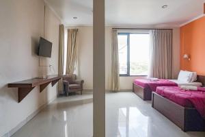 una camera d'albergo con due letti e una finestra di Taxa Uma Guest House a Kuta