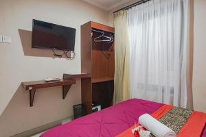 una camera con letto, TV e finestra di Taxa Uma Guest House a Kuta