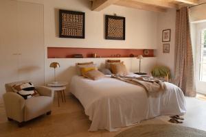 um quarto com uma grande cama branca e uma cadeira em L'Héritier, maison climatisée, 12pers avec piscine em Marzens