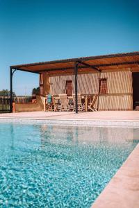 uma piscina com cadeiras e um pavilhão em L'Héritier, maison climatisée, 12pers avec piscine em Marzens