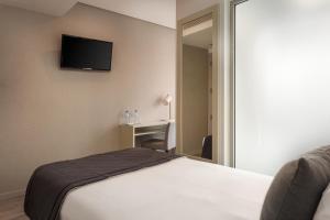 a bedroom with a bed and a television on the wall at Empire Marquês Hotel in Lisbon
