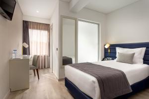 a hotel room with a bed and a desk and a window at Empire Marquês Hotel in Lisbon