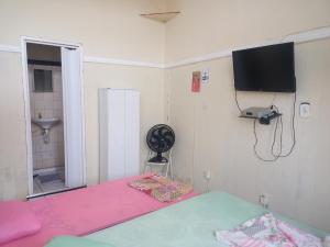 a bedroom with a pink bed and a television on the wall at Casa de hospedagem in Aparecida