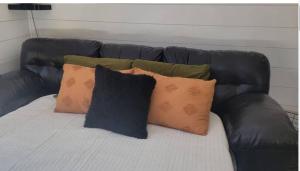 a black leather couch with several pillows on it at Modern A Frame in the woods. Pet friendly in Brook Park