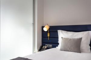 a bed with a blue headboard and a lamp and a phone at Empire Marquês Hotel in Lisbon