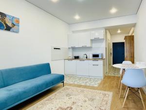 a living room with a blue couch and a kitchen at Bright Studio with Mountain View in Almaty