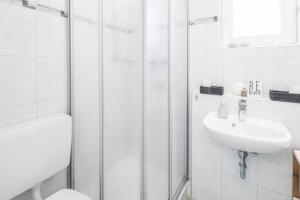 a white bathroom with a sink and a shower at City Apartment Lüneburg in Lüneburg