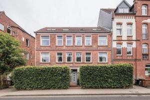 a large brick building with bushes in front of it at City Apartment Lüneburg in Lüneburg