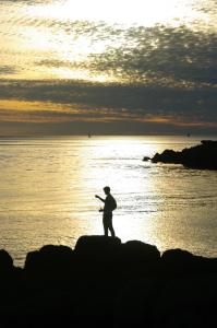 a man is standing on a rock in the ocean at A l'Ombre des Pommiers in Ergué-Gabéric