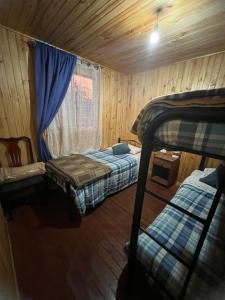 a small room with two beds and a window at Cabañas Vista Hermosa Radal 7 Tazas in El Torreón