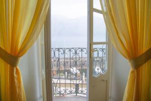 una puerta abierta a un balcón con cortinas amarillas en Casa Rossana - WelcHome, en Cannobio