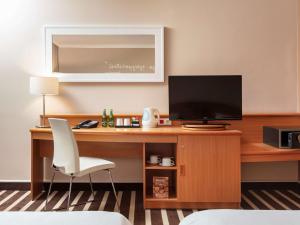 a room with a desk with a television and a chair at Novotel Poznan Centrum in Poznań