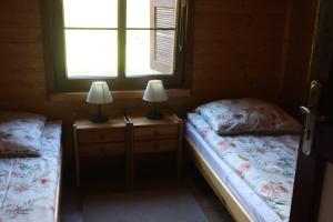 two beds in a room with a window and two lamps at Domek Letniskowy in Mrągowo