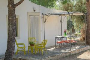 un patio con sillas, una mesa y una sombrilla en Agriturismo Madonna Incoronata, en Mattinata